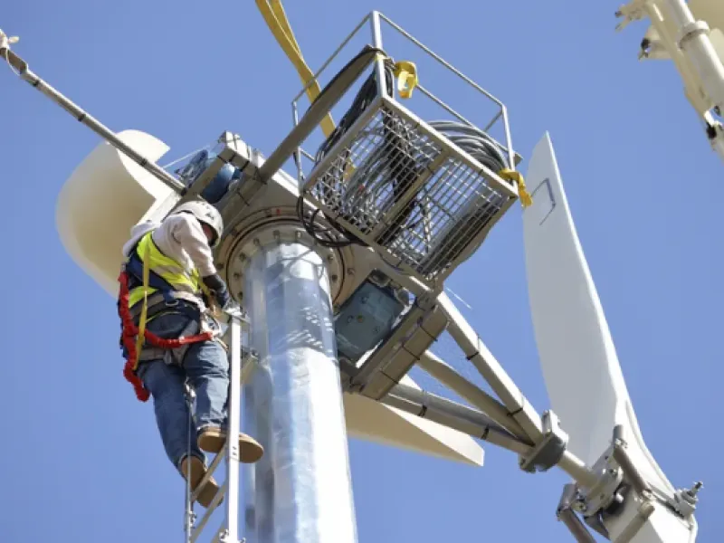 A wind turbine technician climbs to the top of a turbine