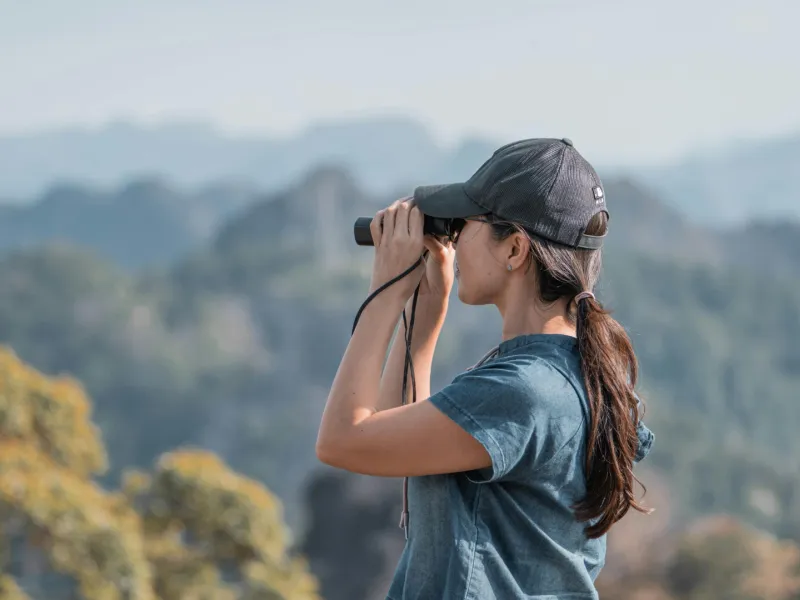 Woman with binoculars looking out at landscape