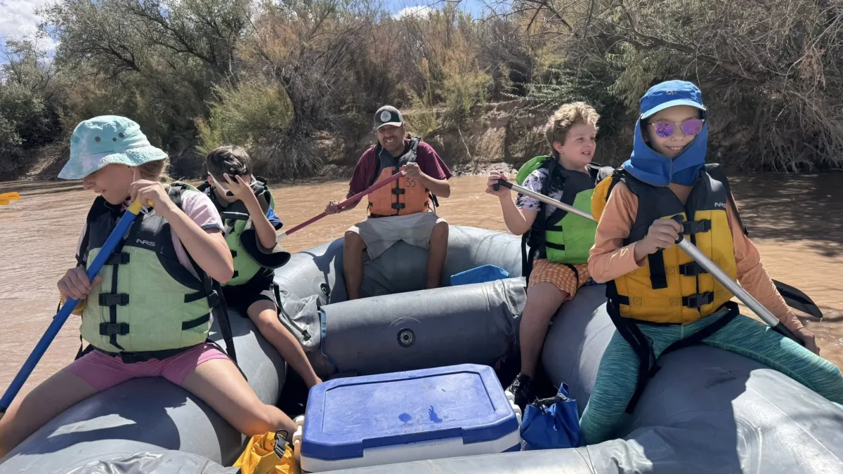 a group of young people paddle a raft