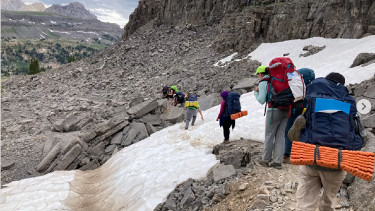 Teton Science School group of teens passes by snow patch high on a rocky mountain