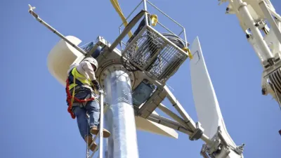 A wind turbine technician climbs to the top of a turbine