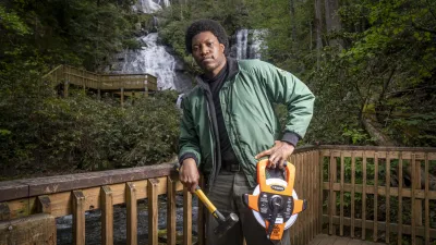 A forest engineer stands on a wooden platform with a hammer and measuring tape