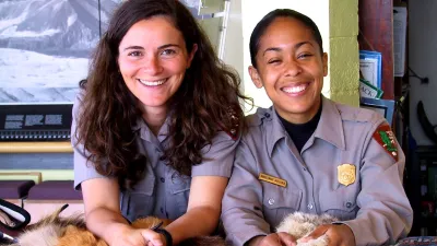 Two National Park Service employees smile while sitting at a desk