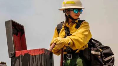 A woman wildfighter stands near an open box of equipment
