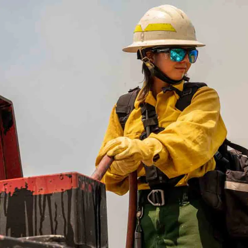 A woman wildfighter stands near an open box of equipment